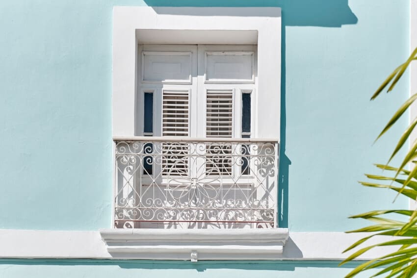 White window with small french wrought iron false balcony in blue building