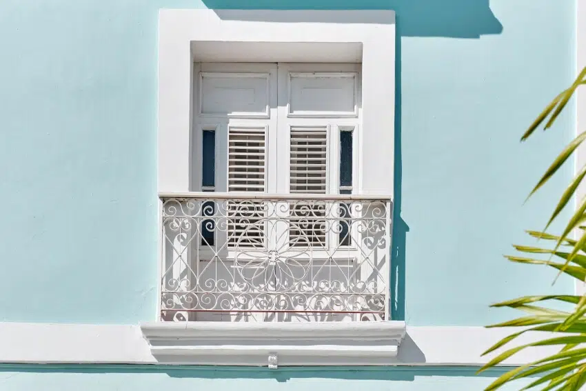 White window with small french wrought iron false ledge in blue building