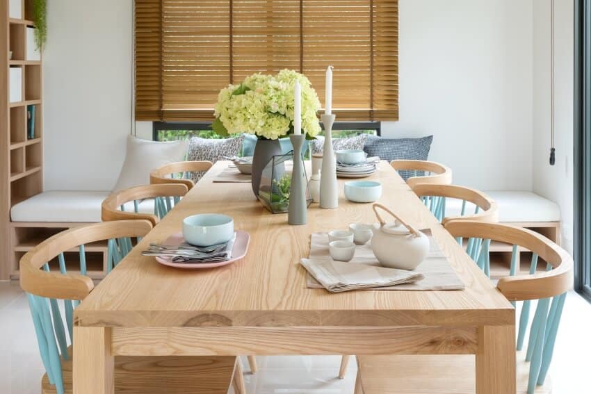 Wooden dining table in modern dining room with table set and vase of plants