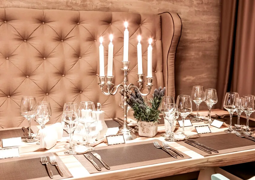 A wooden table with candles in candelabra glasses and silverware