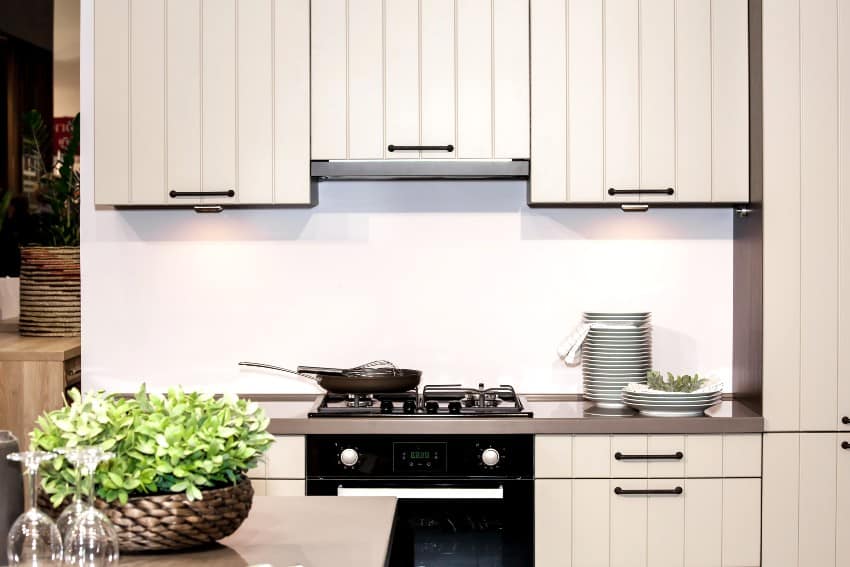 Light kitchen with grooved cabinets, plates on countertop and frying pan on stove