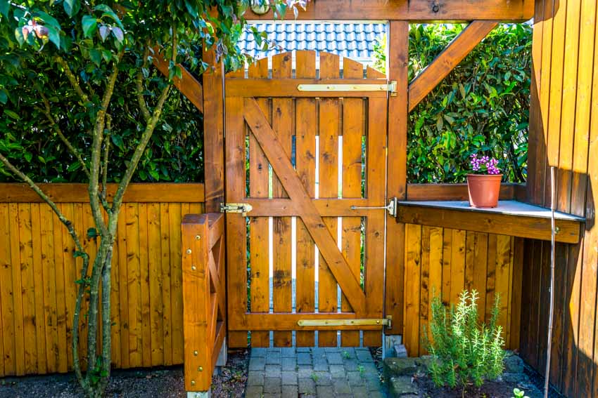 Backyard with wood fence, plants, small tree, and fence gate latch