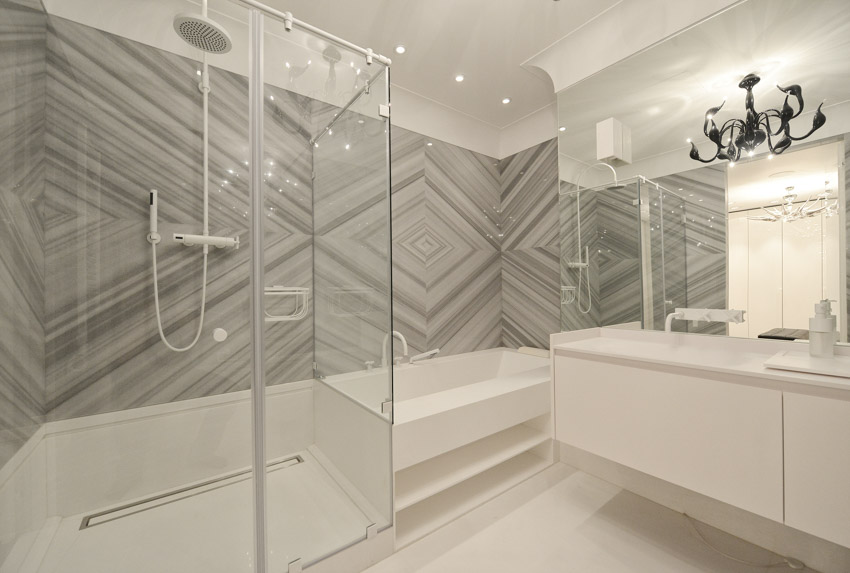 Bathroom with beautiful large format tile, shower wall, tub, glass enclosure, countertop, mirror, and showerhead