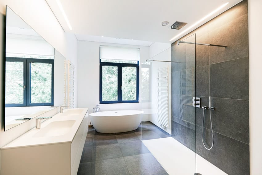 Bathroom with floor to ceiling tile shower, glass enclosure, tub, countertop, mirror, and windows