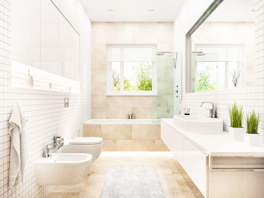 Bathroom with floor to ceiling tiles, toilet, bidet, tub, mirror, countertop, floating vanity, and mirror