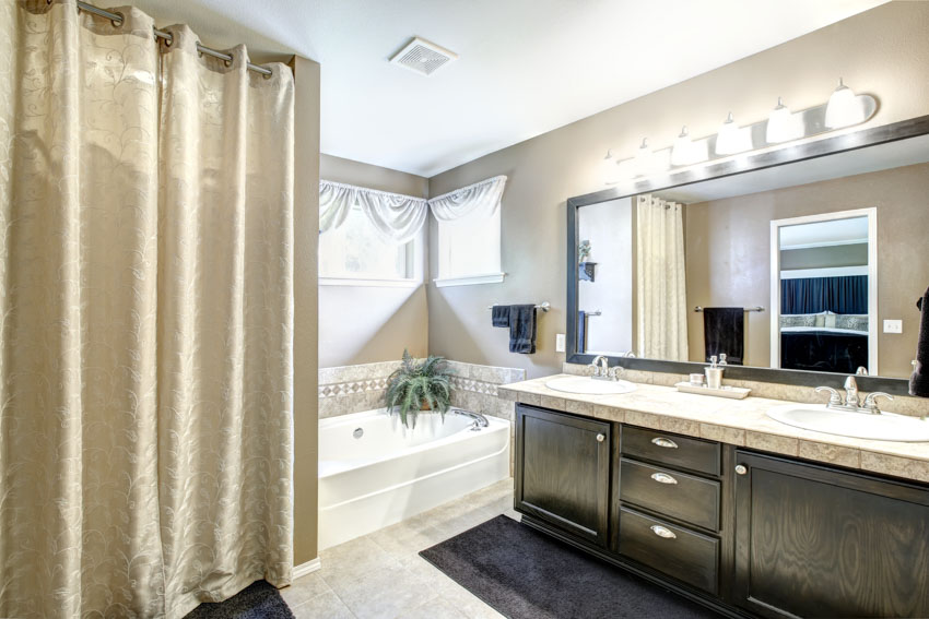 Bathroom with hookless shower curtain, tub, vanity area, mirror, countertop, and windows