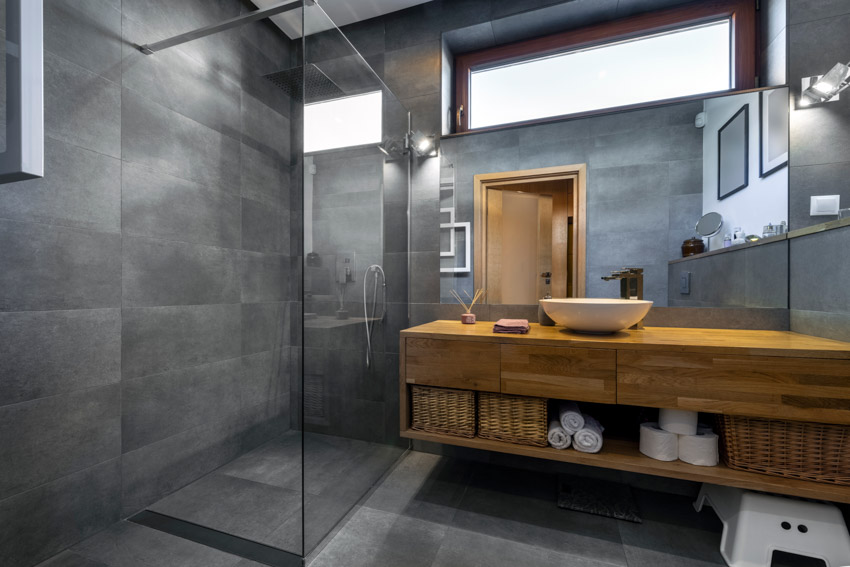 Bathroom with large format tile, shower, glass enclosure, floating wood countertop, sink, mirror, and window