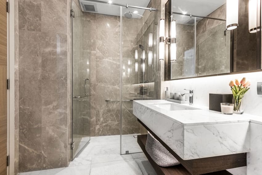 Bathroom with marble wall, glass door, shower area, mirror, and quartz countertop