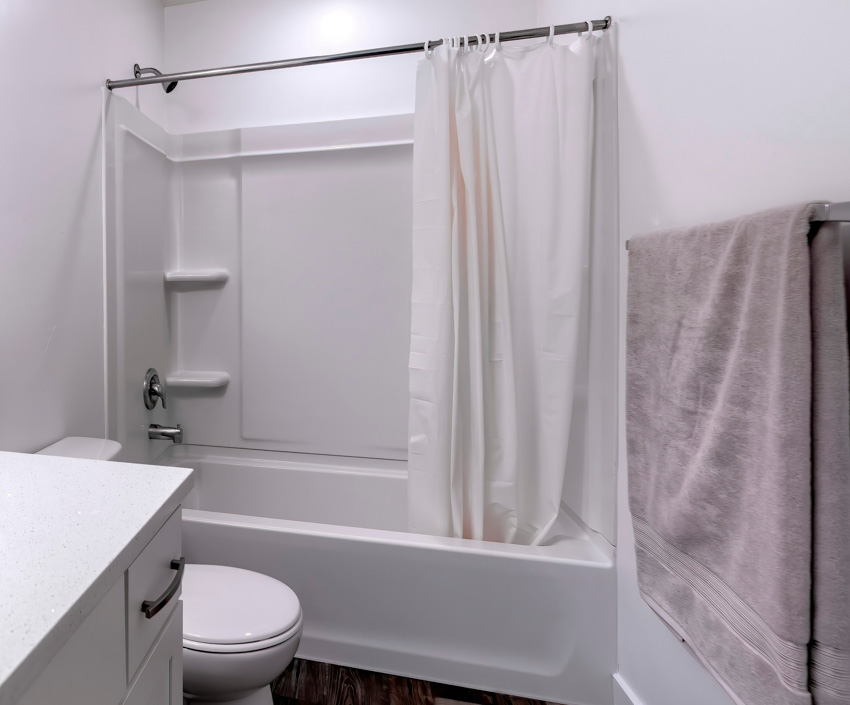 Bathroom with curtain rod, tub, toilet, and towel holder