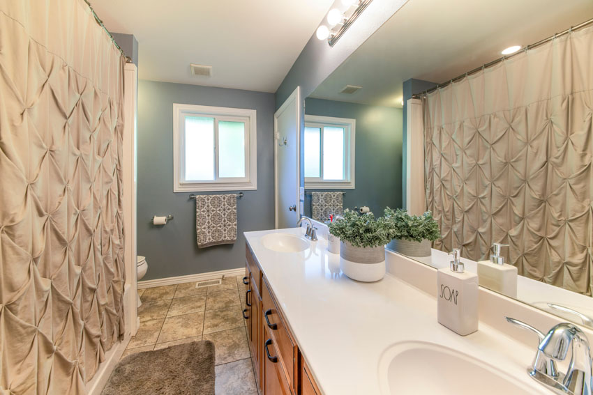 Bathroom with shower curtain, sink, countertop, tile floors, faucet, and window