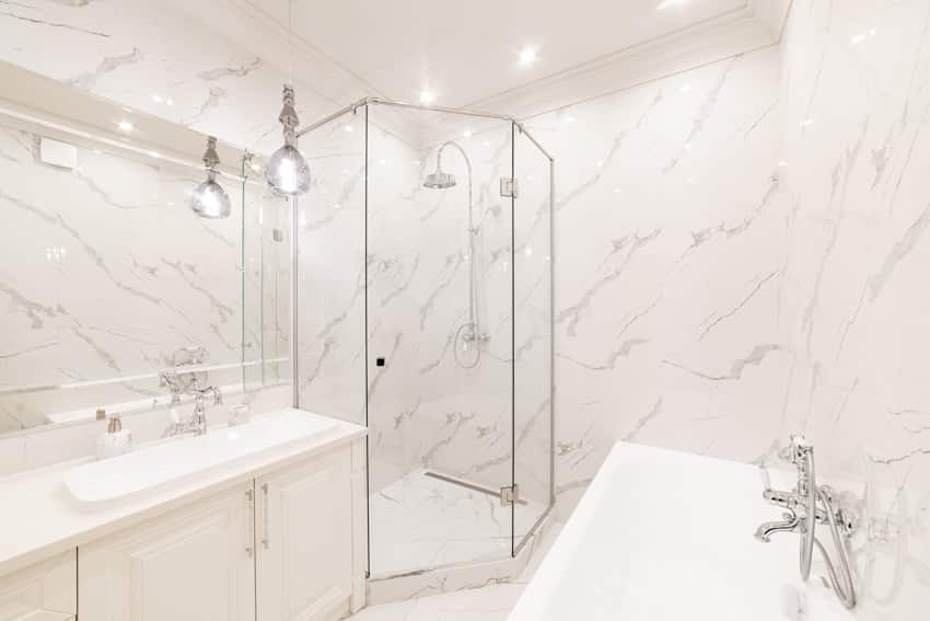 Bathroom with Statuario marble walls, shower enclosure, countertops, sink, ceiling lights, and cabinets