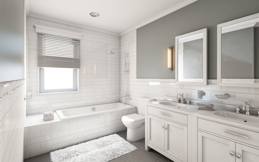 Bathroom with subway tile wall, window, tub, mirror, vanity area, countertop, cabinets, and toilet