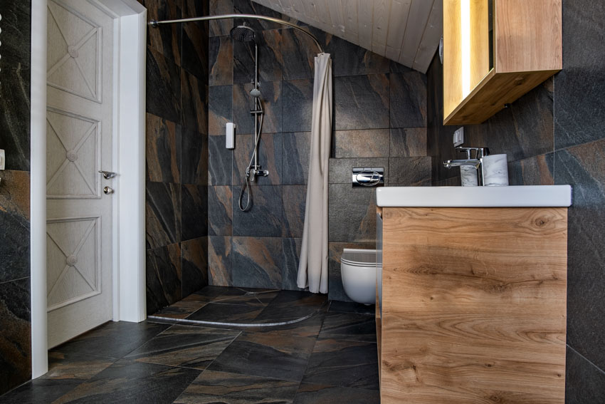 Bathroom with tile floors, shower curtain, vanity area, countertop, toilet, and door