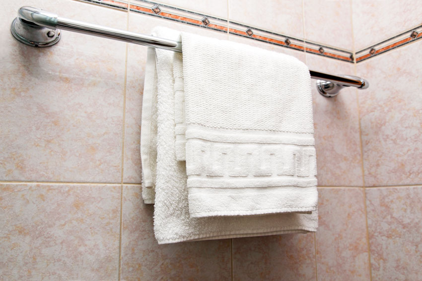 Bathroom with tiled wall, towel holder, and white bath towels