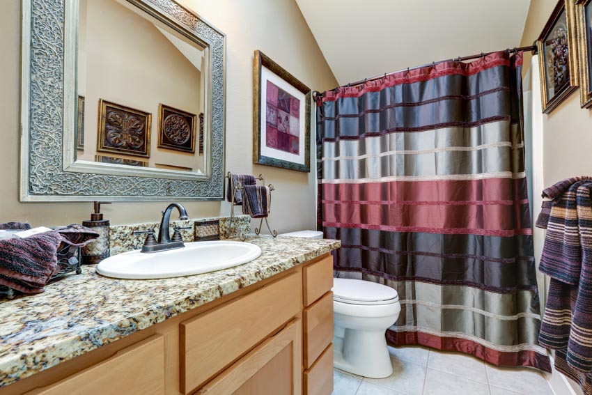 Bathroom with weighted shower curtain, granite countertop, sink, mirror, and toilet