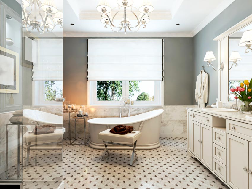Bathroom with windows, Roman shades, tub, patterned floor, vanity area, ottoman, drawers, and mirror