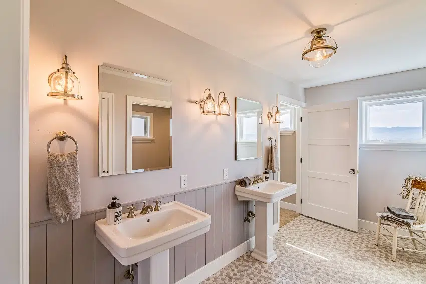 Beautiful bathroom with gray shiplap accent wall, double pedestal sinks and multiple sconce lights