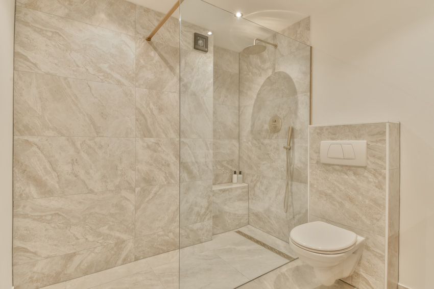 Beautiful bathroom with large format tile, shower, glass divider, and toilet