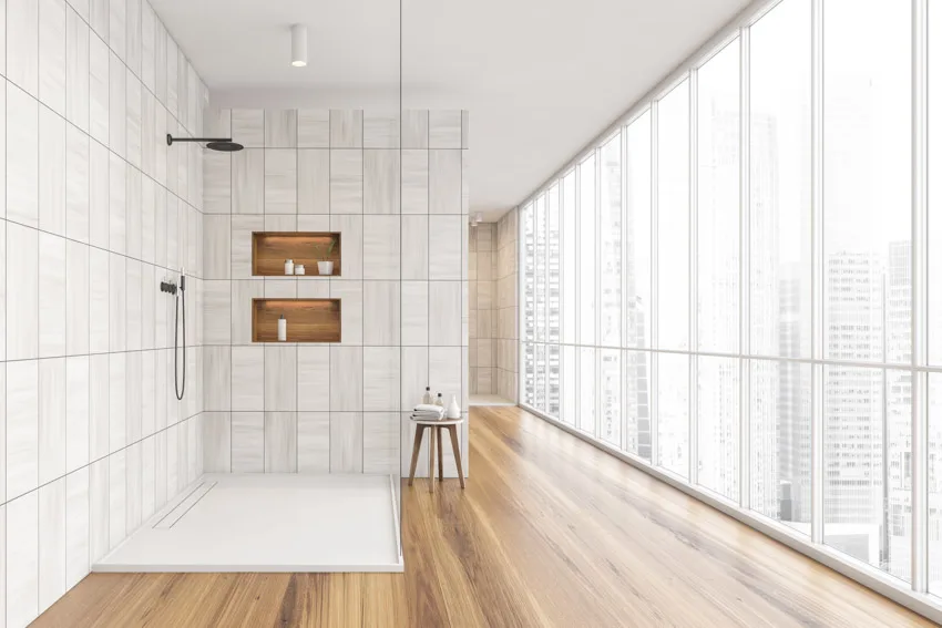 Bathroom with ceiling to floor windows, alcove walls and white shower flooring