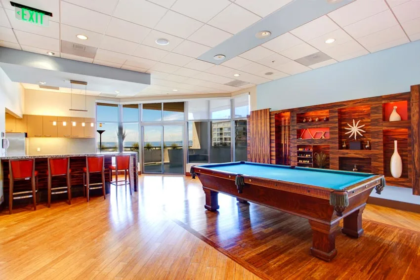 Beautiful game room with hardwood floors, pool table, bar area, chairs, and windows