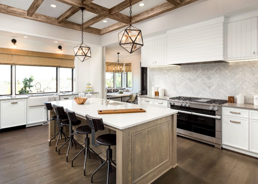 Beautiful kitchen interior with white grooved cabinets, island and pendant light fixtures