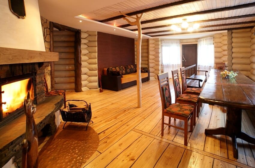 Big and bright wooden interior with fireplace, wooden furniture and pine wood flooring