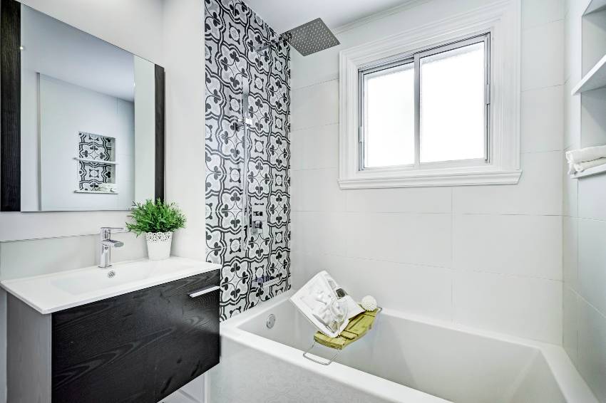 Black and white bathroom interior with tiled accent wall in the shower and a bathtub with essentials