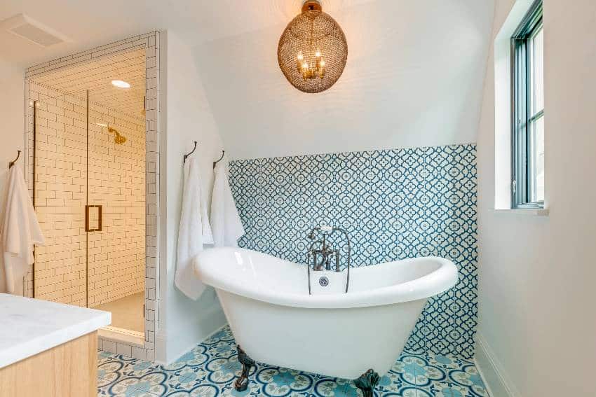 A blue and white patterned tile bathroom accent wall with free standing bathtub