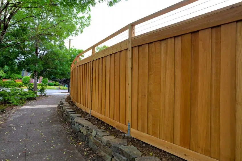 Raised fence panels with stacked stone border near walkway