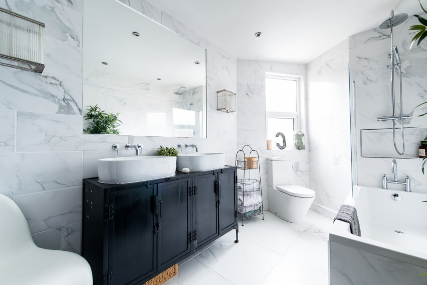 Clean bright stylish designer bathroom with black vanity countertop, bathtub