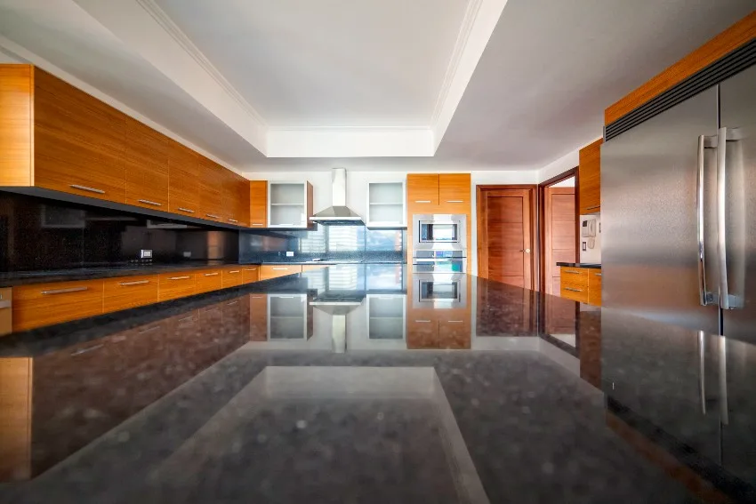 Contemporary kitchen with laminated wood cabinets, stainless steel appliances, and island with granite countertop 