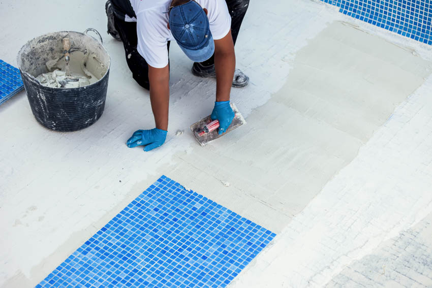 Contractor applying plaster and tiles on swimming pool floor