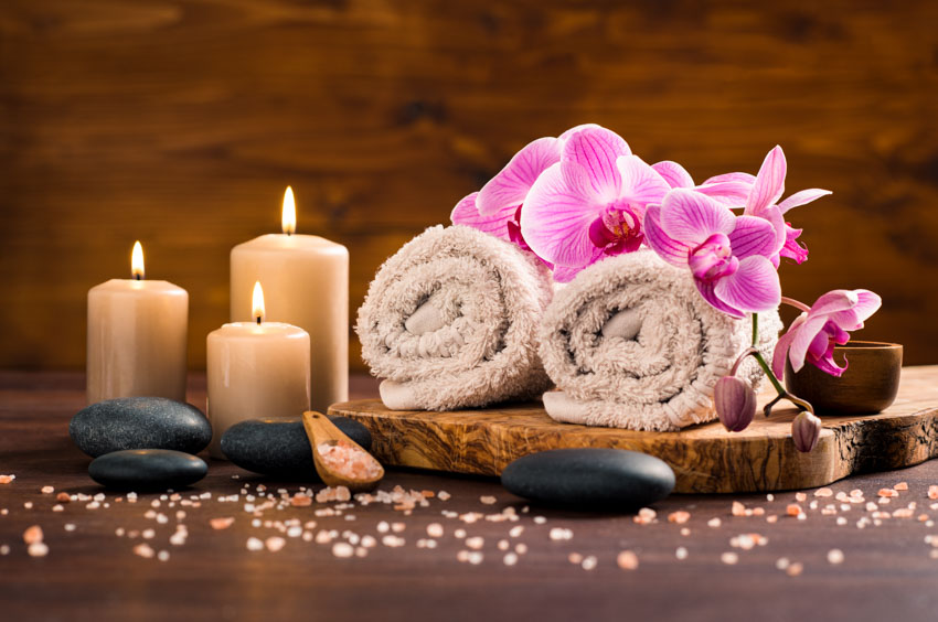 Decorative arrangement of spa towels candles, and massage rocks