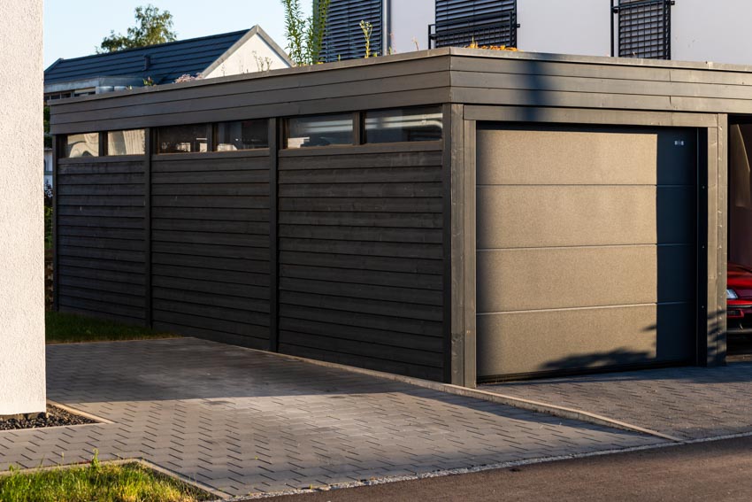 Detached drive through garage with flat roof, and black siding