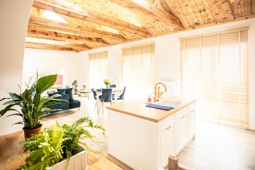 Dining area and kitchen space combined with wood blinds, wooden beam ceiling, island and countertop