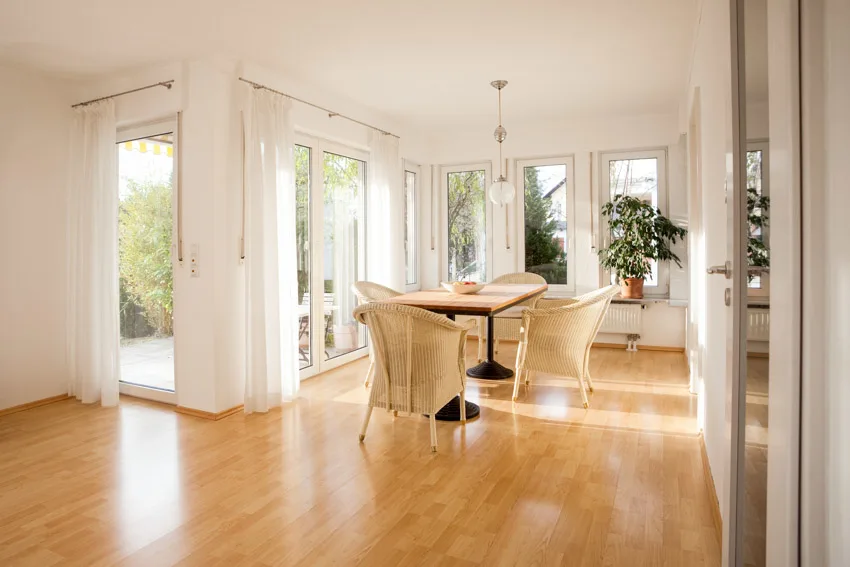 Dining room with birch wood floors, table, chairs, curtains, glass door, and windows
