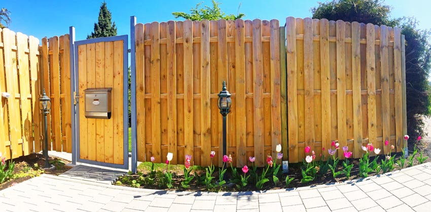 Dog ear shadow box fence made of wood with door and flowers
