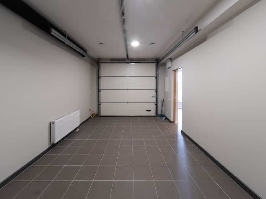 Empty garage with door, floor tiles and ceiling light