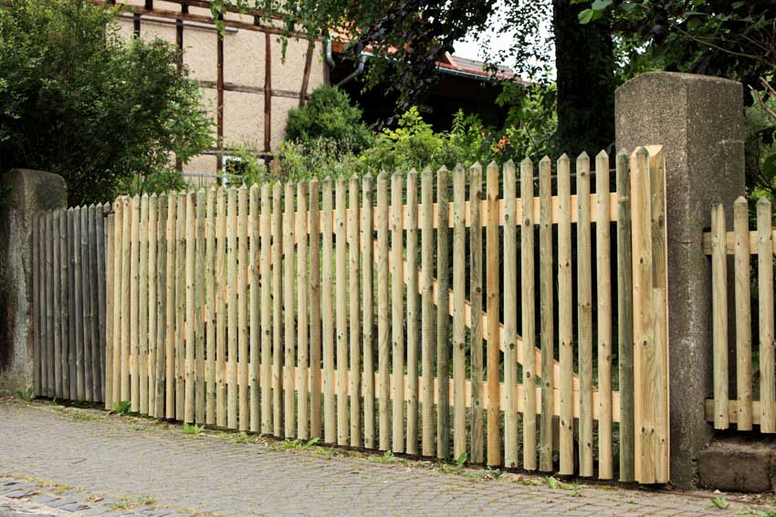 Unpainted wooden gate attached to concrete pillars