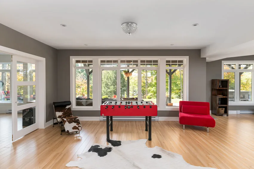 Game room with foosball table, wood floors, red chair, and windows