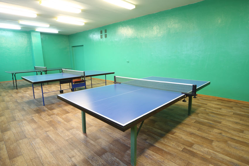 Room with ping pong tables, ceiling lights, and wood floors