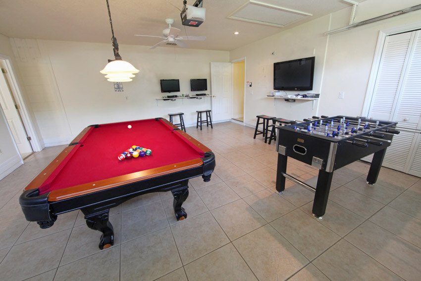 Room with tile floors, gaming table, foosball, chairs, pendant lights, and television