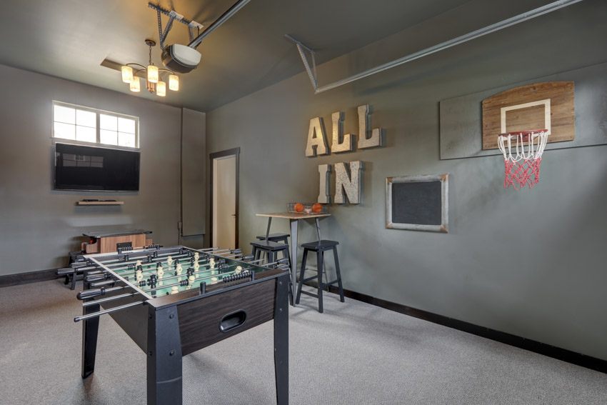 Garage game room with concrete floor, foosball table, stool, television, and window