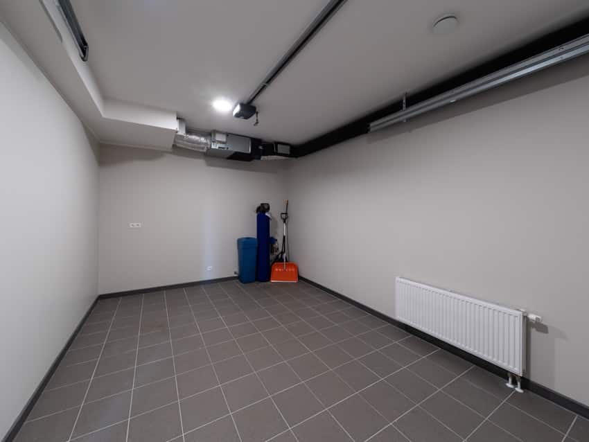 Garage space with porcelain floor tiles, white walls, and ceiling light