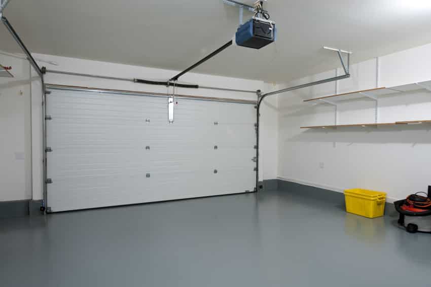 Garage with epoxy floor, retractable door, shelves, and white wall