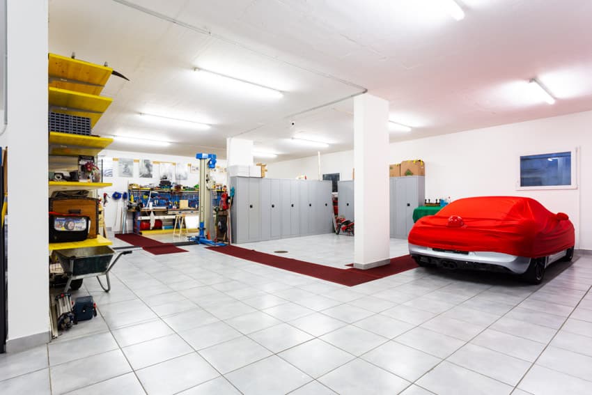 Garage with porcelain floor tiles, car shelves, work area, and ceiling lights
