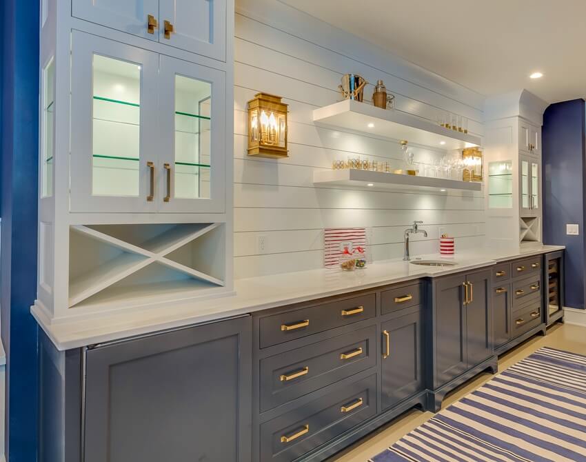 Kitchen with shiplap backsplash, blue cabinets, shelves, and warm lighting