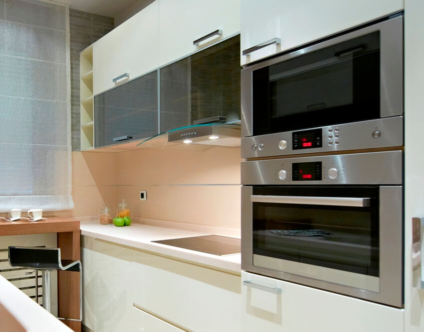 A gorgeous kitchen with white cabinets, built in microwave and electric appliances