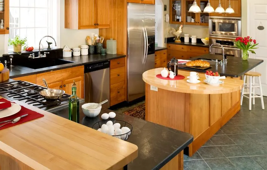Gourmet kitchen with breakfast on bluestone countertop, a stove, wooden island and cabinets