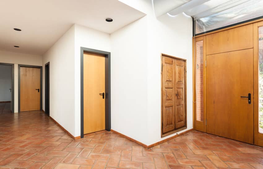 House entrance way with wood doors, ceiling lights, and brick floors